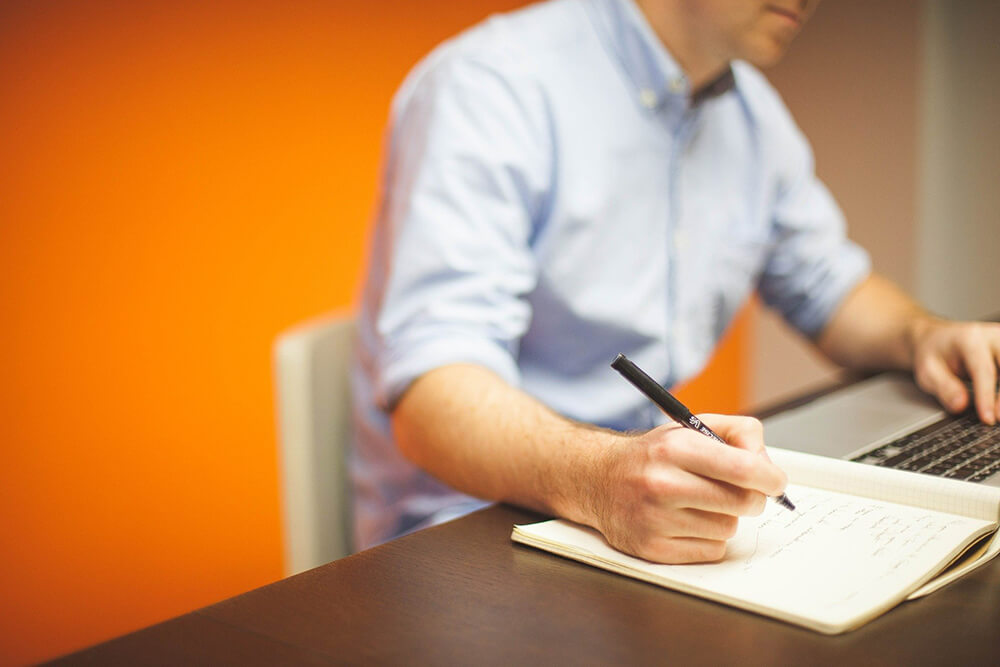 Person on laptop and taking notes